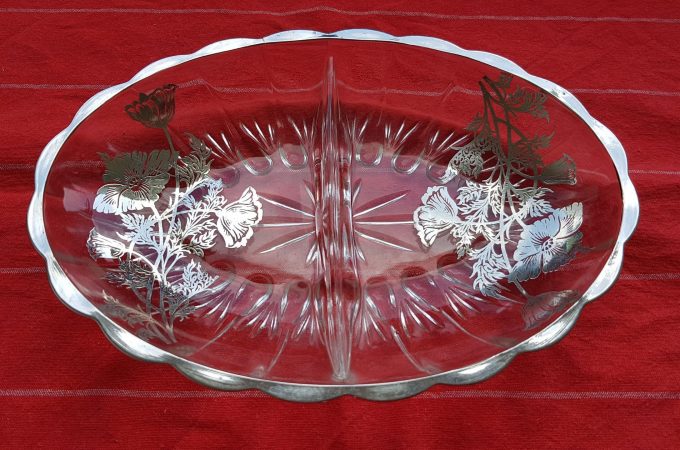 Serveerschaaltje van glas. Ovaal van vorm met zilveren rand. Ingelegd met bloemen van zilver. 1